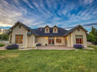 This stunning home features a beautifully manicured lawn and a charming patio area, perfect for outdoor entertaining.