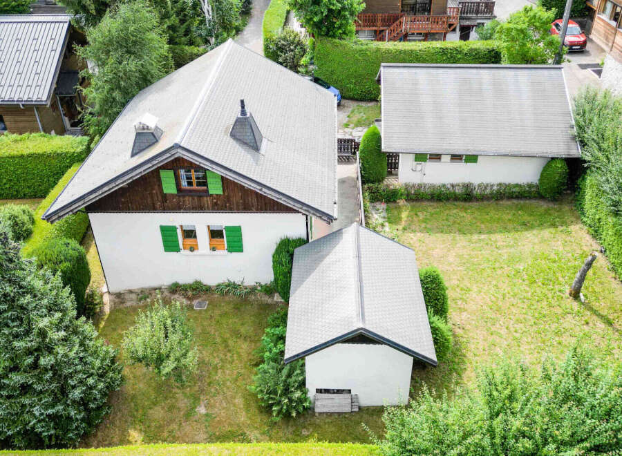 Discover this charming property featuring a main house with a distinctive roofline and green shutters, complemented by a separate garage or outbuilding.