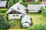 Discover this charming property featuring a main house with a distinctive roofline and green shutters, complemented by a separate garage or outbuilding.