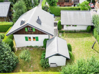 Discover this charming property featuring a main house with a distinctive roofline and green shutters, complemented by a separate garage or outbuilding.
