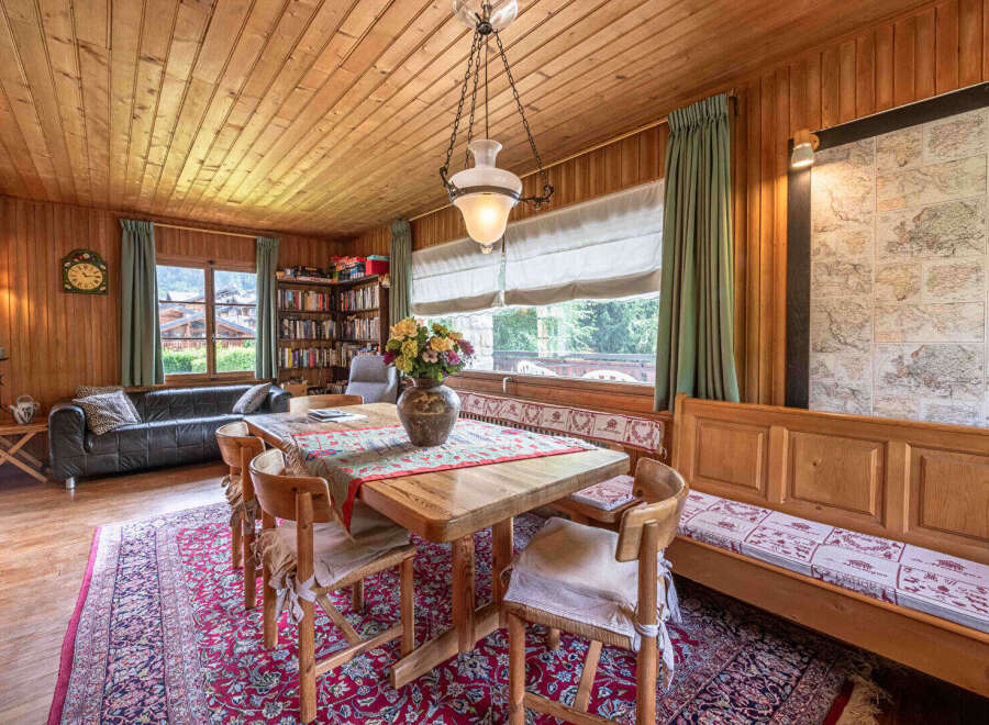 Experience cozy living in this charming dining area, featuring a rustic wooden table adorned with a vibrant floral centerpiece.