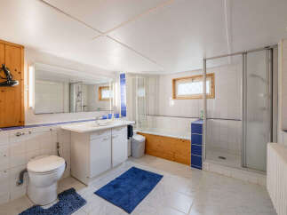 This bright and functional bathroom features a spacious vanity with ample storage, a comfortable toilet, and a separate shower stall.