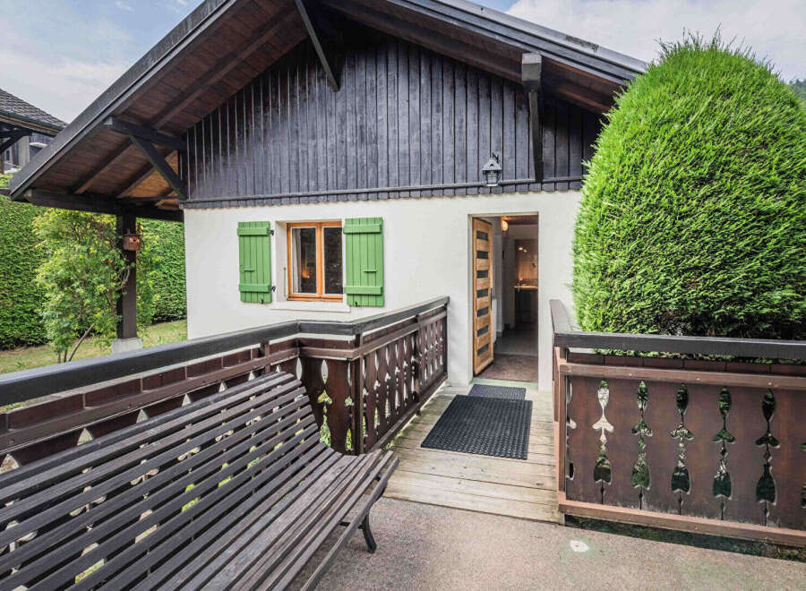 Charming alpine cottage featuring a rustic wooden deck and a welcoming entrance.