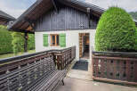 Charming alpine cottage featuring a rustic wooden deck and a welcoming entrance.