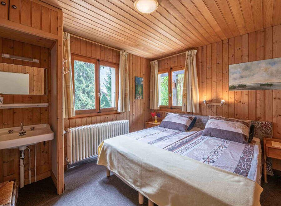 Experience rustic charm in this cozy bedroom featuring warm wood paneling throughout.