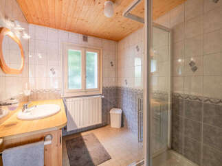 This charming bathroom features a wooden vanity with a white sink and a sleek chrome faucet, complemented by a large oval mirror with a wooden frame.