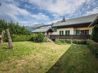 Experience the charm of this alpine property featuring a picturesque garden and a traditional wooden balcony overlooking the majestic mountains.