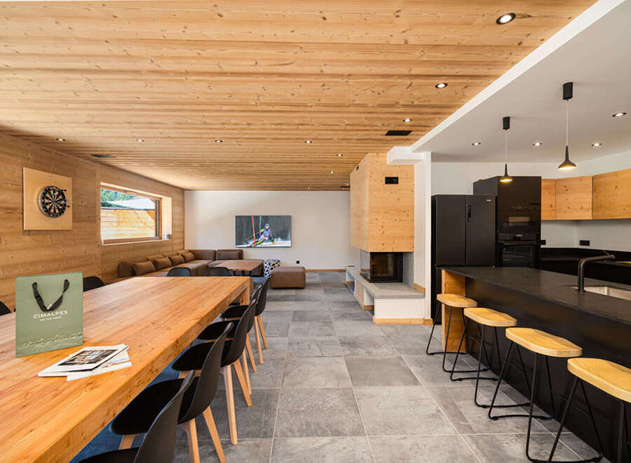Experience luxury mountain living in this stunning chalet, featuring a spacious open-plan living area with a modern kitchen and a cozy fireplace.