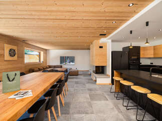 Experience luxury mountain living in this stunning chalet, featuring a spacious open-plan living area with a modern kitchen and a cozy fireplace.