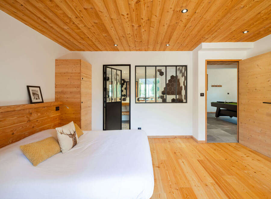 Experience rustic charm in this mountain-inspired bedroom, featuring a cozy bed with decorative pillows and a striking wooden headboard.