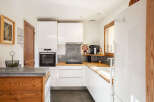 Discover this modern and functional kitchen, featuring sleek white cabinetry and a built-in oven.