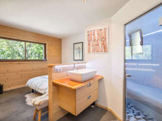 Experience ultimate relaxation in this modern bedroom featuring a unique en-suite bathroom with a vessel sink and a luxurious glass-enclosed shower.