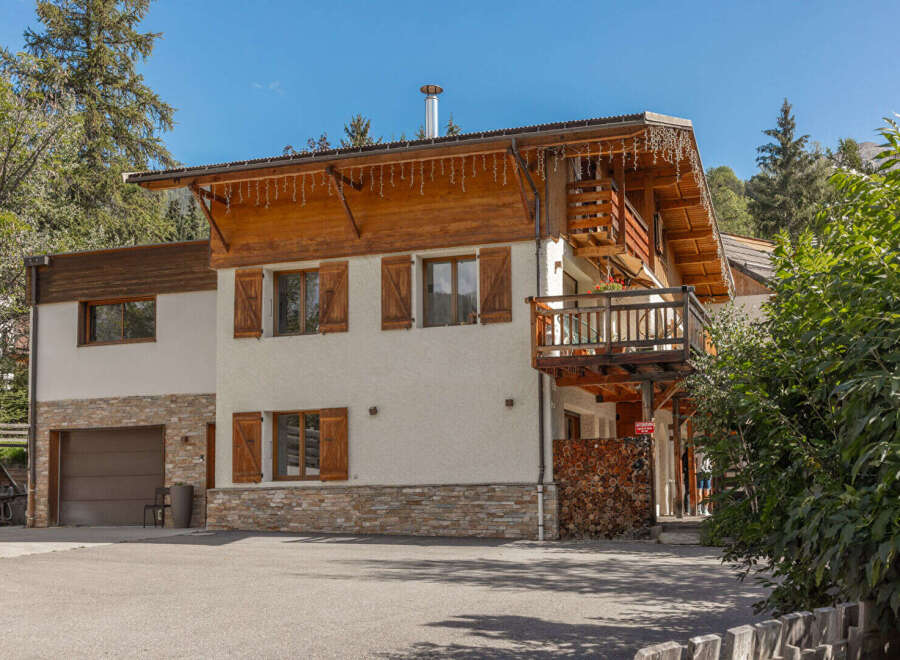 Experience alpine living in this charming chalet featuring a rustic wooden exterior and a spacious balcony perfect for enjoying mountain views.