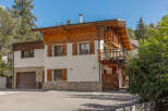 Experience alpine living in this charming chalet featuring a rustic wooden exterior and a spacious balcony perfect for enjoying mountain views.