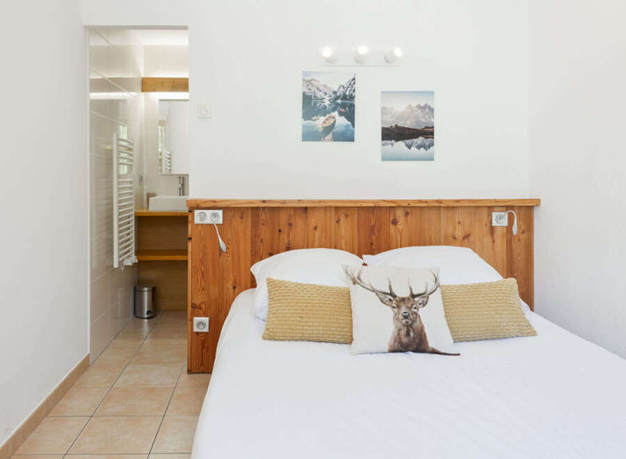 Experience comfort and style in this charming bedroom featuring a rustic wooden headboard and a unique deer-themed accent pillow.