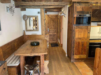 Experience rustic charm in this cozy dining area, featuring a wooden banquette and a sturdy wooden table perfect for family meals.