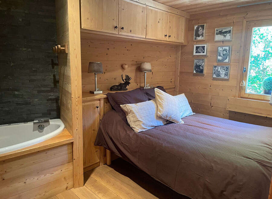 Experience rustic charm in this cozy bedroom featuring a comfortable bed adorned with plush pillows and a rich brown duvet.