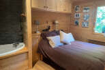 Experience rustic charm in this cozy bedroom featuring a comfortable bed adorned with plush pillows and a rich brown duvet.