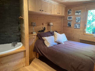 Experience rustic charm in this cozy bedroom featuring a comfortable bed adorned with plush pillows and a rich brown duvet.