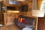 Experience rustic charm in this cozy mountain retreat, featuring a warm wooden interior and a comfortable living area.