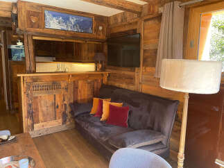 Experience rustic charm in this cozy mountain retreat, featuring a warm wooden interior and a comfortable living area.