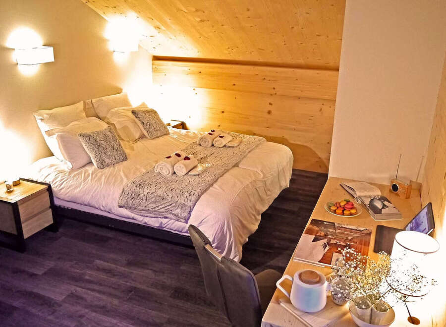 Experience ultimate comfort in this charming attic bedroom, featuring a cozy bed adorned with plush pillows and soft throws.