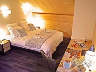 Experience ultimate comfort in this charming attic bedroom, featuring a cozy bed adorned with plush pillows and soft throws.