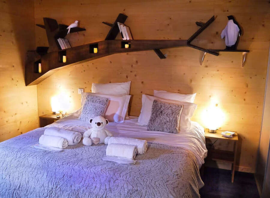 Experience cozy comfort in this charming wooden cabin bedroom, featuring a plush queen-sized bed adorned with soft pillows and throws.