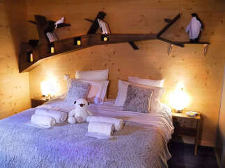 Experience cozy comfort in this charming wooden cabin bedroom, featuring a plush queen-sized bed adorned with soft pillows and throws.