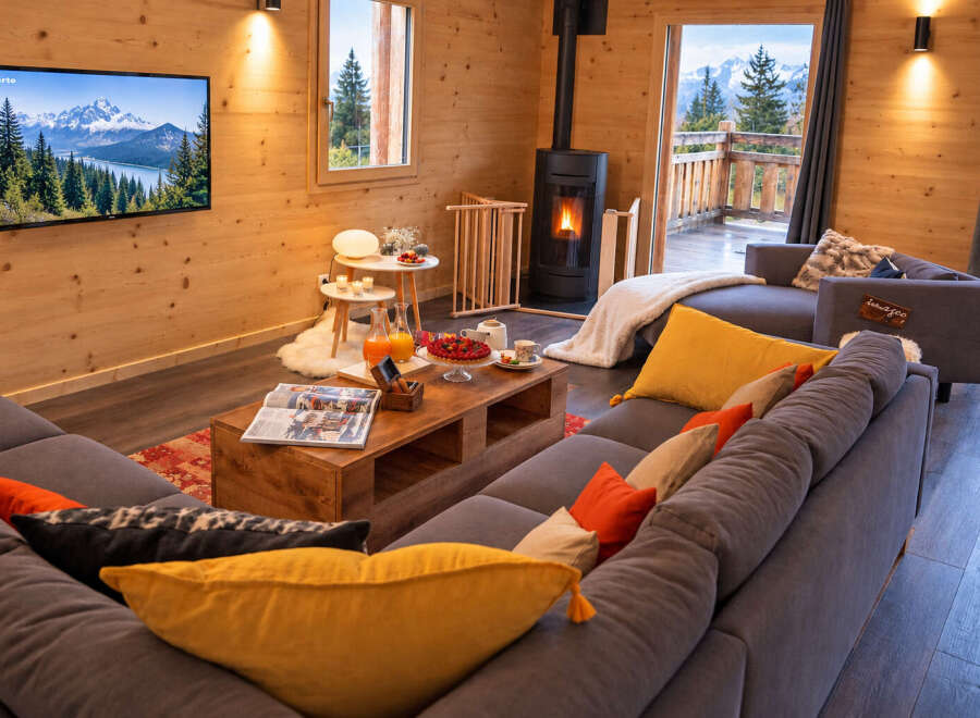 Experience cozy mountain living in this charming wooden cabin, featuring a modern fireplace and a spacious sectional sofa perfect for relaxation.