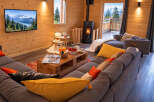 Experience cozy mountain living in this charming wooden cabin, featuring a modern fireplace and a spacious sectional sofa perfect for relaxation.
