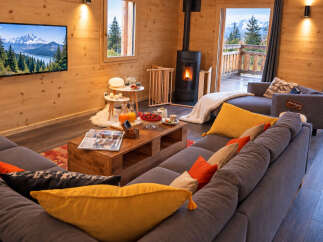 Experience cozy mountain living in this charming wooden cabin, featuring a modern fireplace and a spacious sectional sofa perfect for relaxation.
