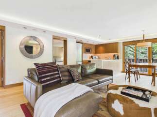 Experience modern living in this open-concept space featuring a plush leather sofa and a stylish cowhide ottoman.