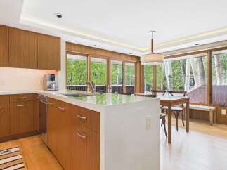 This modern kitchen boasts sleek, warm wood cabinetry and a spacious white quartz island, perfect for meal preparation and casual dining.