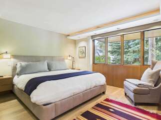 Experience ultimate comfort in this serene bedroom, featuring a plush king-sized bed adorned with crisp white linens and a sophisticated navy blue throw.