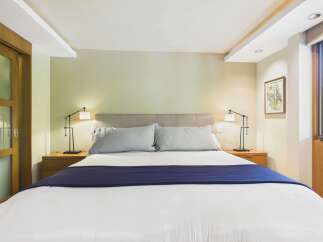 Experience comfort and style in this beautifully appointed bedroom, featuring a plush king-sized bed with crisp white linens and a striking navy blue throw.
