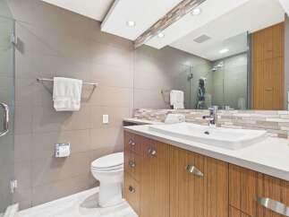 This modern bathroom features a sleek design with large grey tiled walls and a complementary mosaic tile backsplash.
