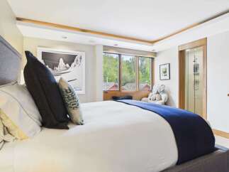 Experience luxury mountain living in this exquisite bedroom featuring a plush king-sized bed adorned with premium linens and decorative pillows.