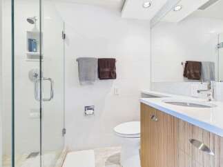 This modern bathroom features a sleek glass-enclosed shower with a rainfall showerhead and a built-in niche for toiletries.