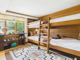 This charming children's bedroom features a space-saving triple bunk bed setup, perfect for sleepovers or large families.