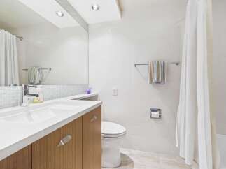 Experience modern comfort in this beautifully appointed bathroom, featuring a sleek vanity with ample storage and a pristine white sink.