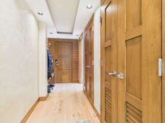 Step into this inviting hallway featuring warm wooden doors and a textured cream wall, creating a sophisticated and welcoming atmosphere.