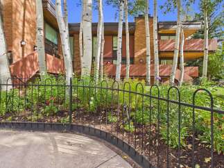 Charming multi-level residence nestled amongst mature aspen trees, offering a unique architectural style with brick and wood accents.