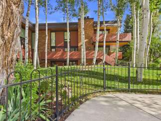 Nestled amongst mature aspen trees, this stunning home offers a unique architectural design with a striking brick facade and warm wood accents.