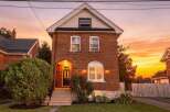 Charming brick home with a welcoming arched entryway and a beautiful arched window, perfect for enjoying the sunset.