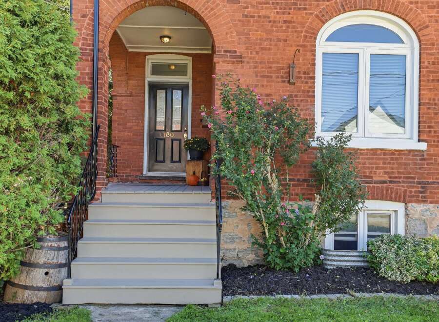 Charming brick home featuring a welcoming arched entryway with a classic black door and elegant sidelights.