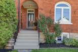 Charming brick home featuring a welcoming arched entryway with a classic black door and elegant sidelights.