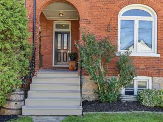 Charming brick home featuring a welcoming arched entryway with a classic black door and elegant sidelights.