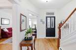 Step into this charming entryway featuring a classic black front door with decorative glass panels, leading to a bright and airy staircase.