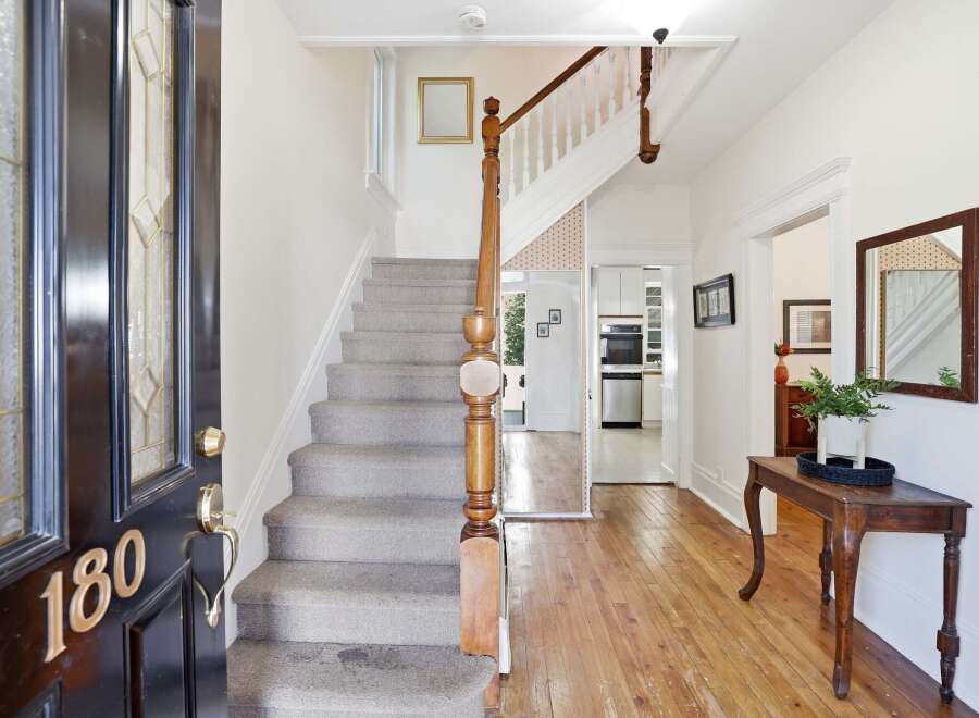 Step into this charming entryway featuring a grand staircase with plush carpeting and a classic wooden banister.